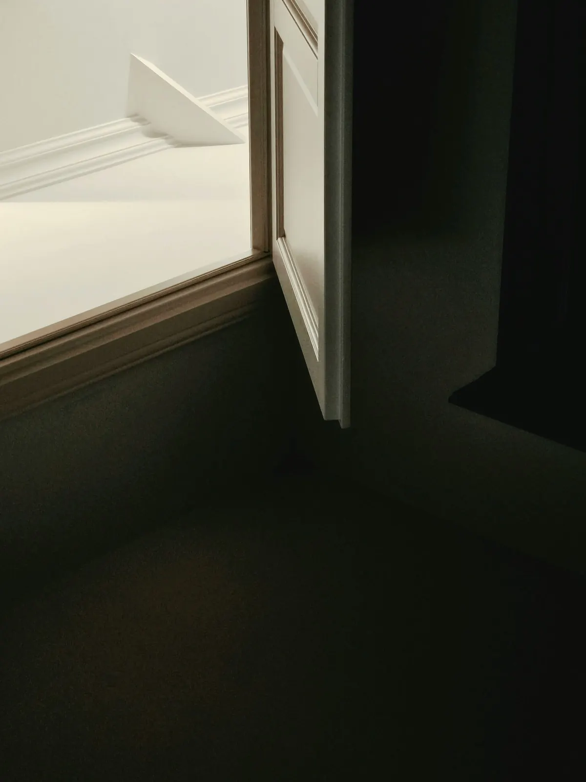 Light and shadow cast across a plain interior wall by a window