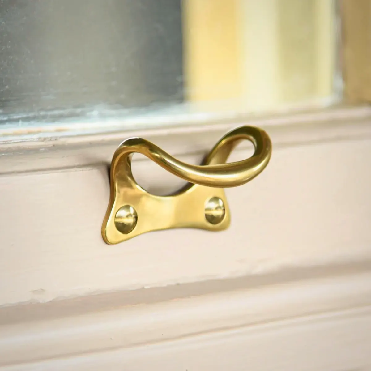 A brass sash lift fixed to the bottom rail of a painted sash
