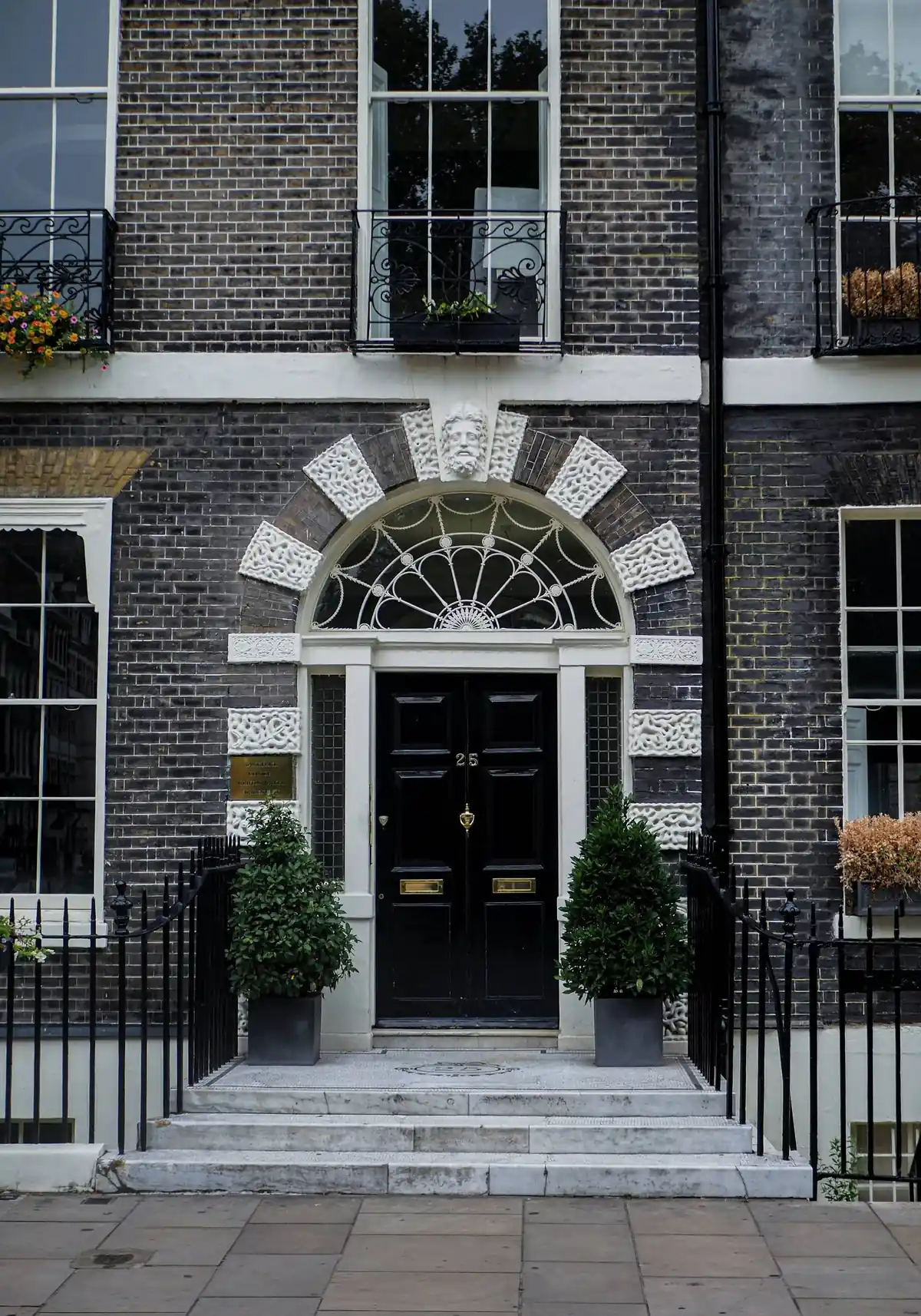 A black-painted Georgian door and fanlight beneath original timber sash windows