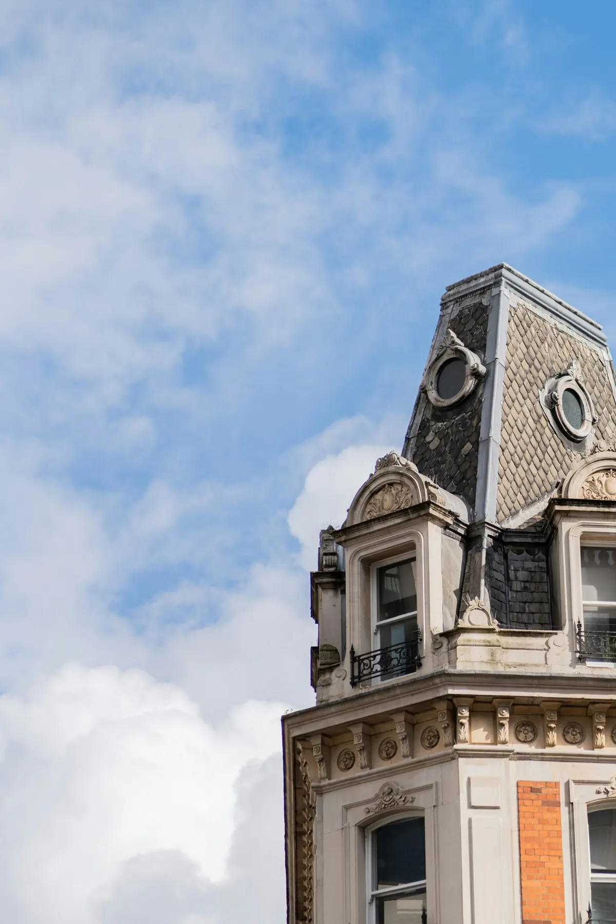 An ornate mansard roofline with dormer windows against open sky