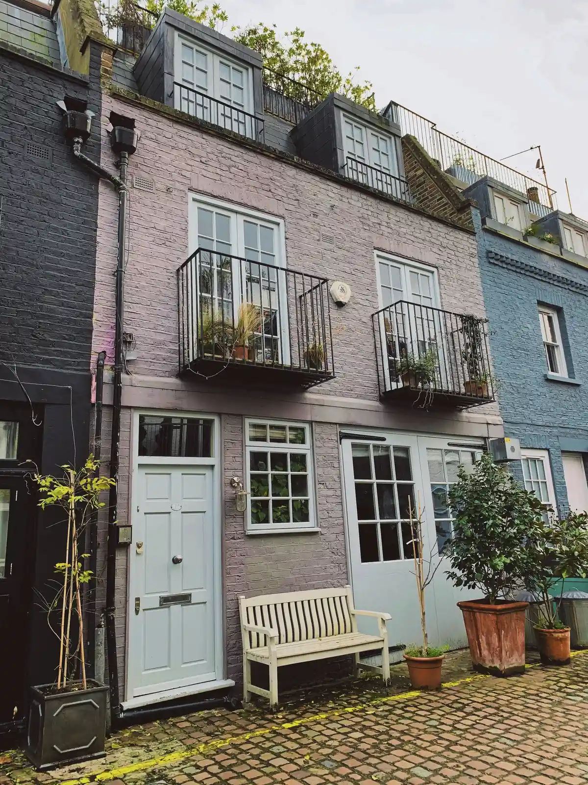 A row of pastel-painted mews houses with timber windows