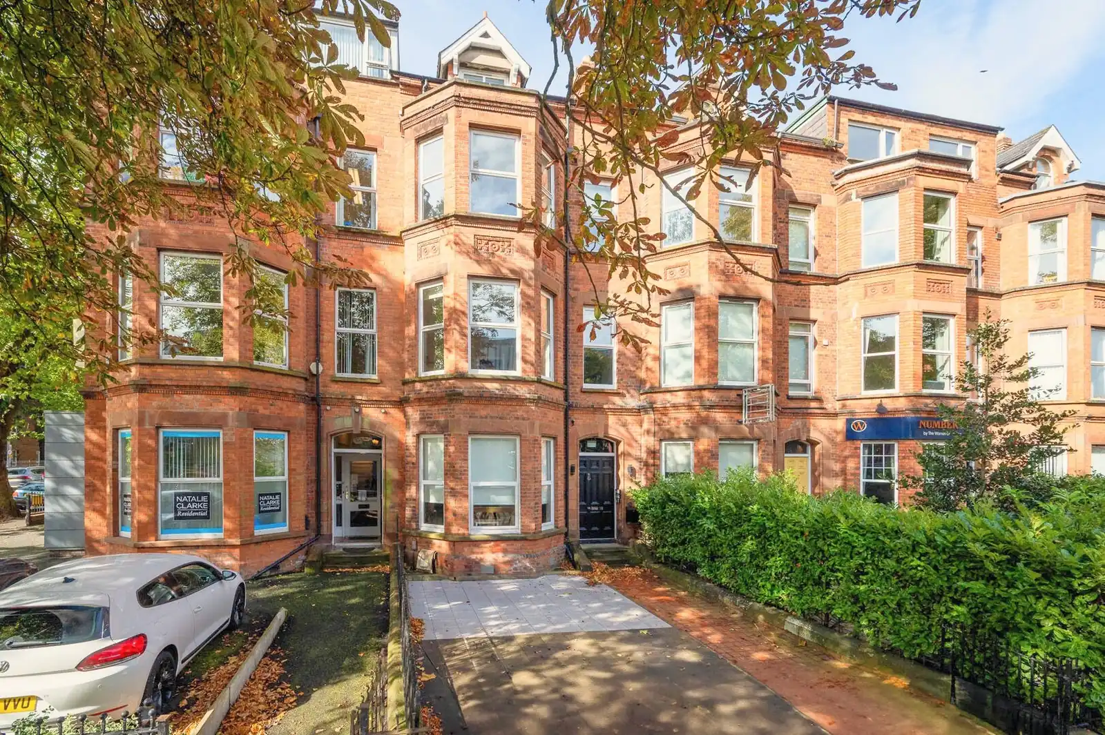 A red brick and sandstone terrace with canted bay windows rising through three floors to gabled dormers