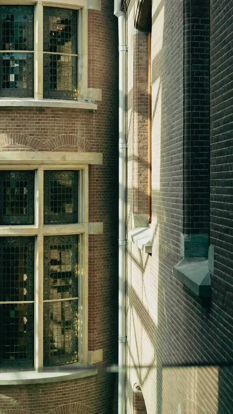 Green-painted timber window frames in a brick elevation, seen obliquely
