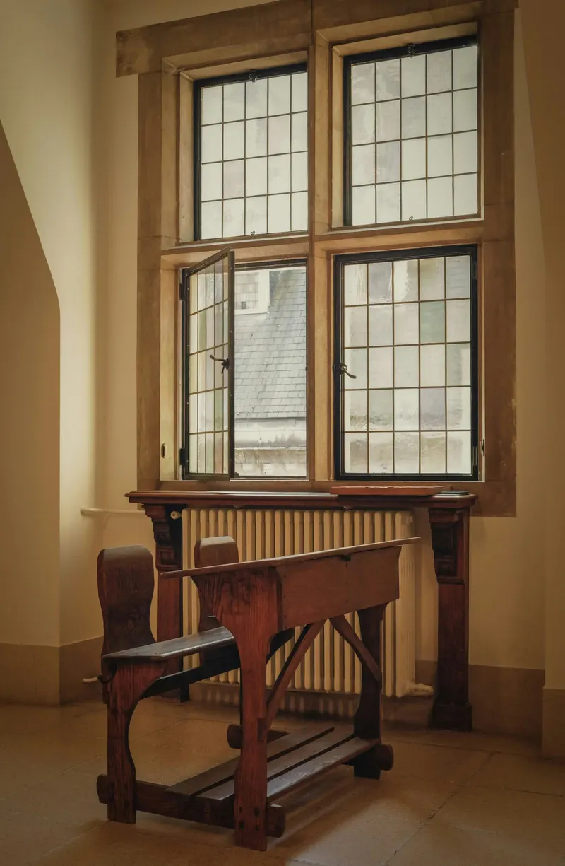 A tall timber window above a desk in warm light